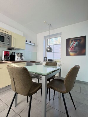 Una cocina moderna con una mesa de comedor, sillas y una cafetera.
