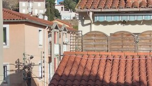 Ett bostadsområde med tak belagda med terrakottafärgade tegelpannor, ett trästaket och en klarblå himmel.