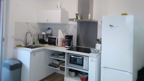 Ett kompakt kök med mikrovågsugn, kaffebryggare och en inbyggd ugn.