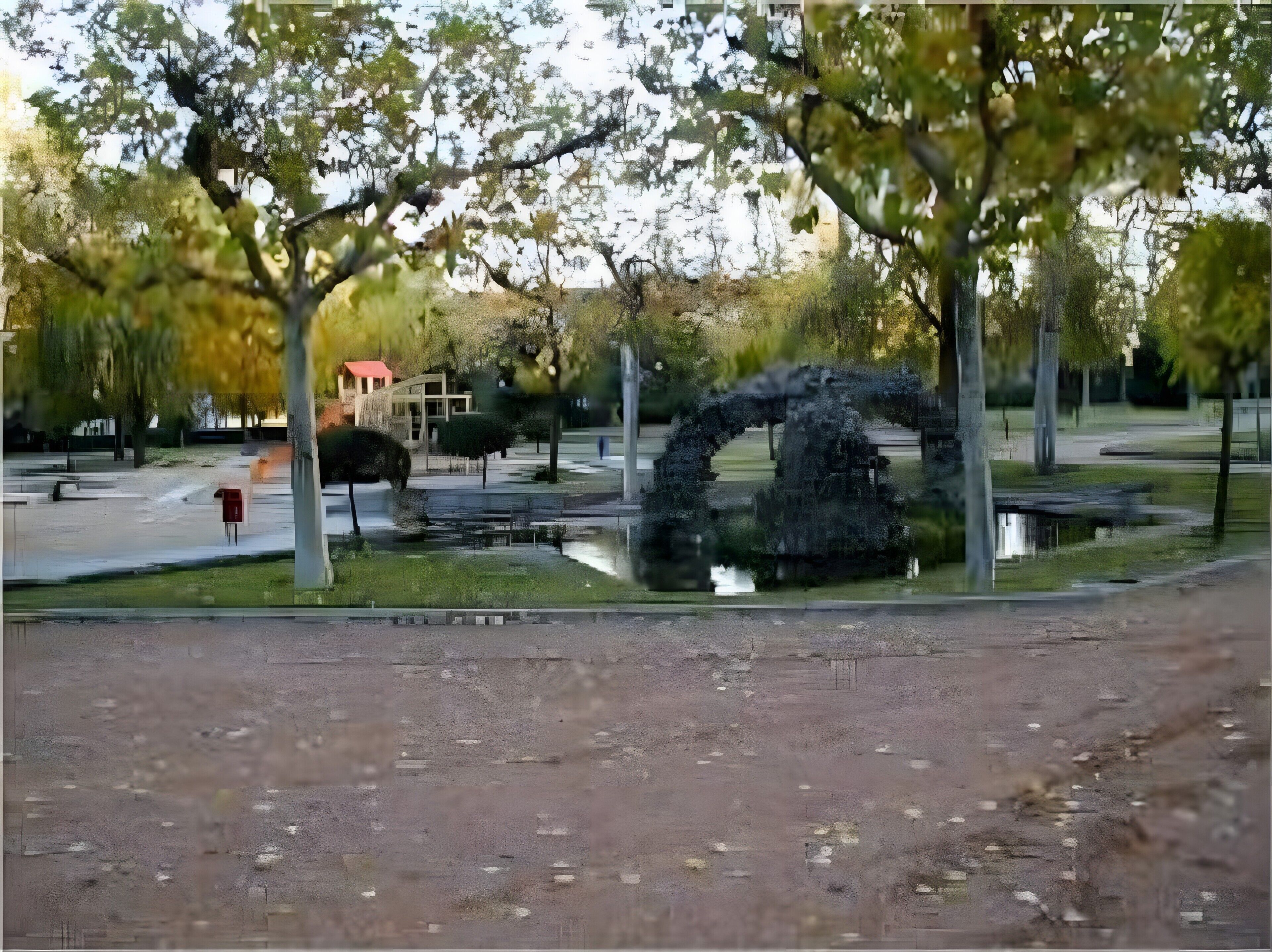 Ein Park mit einer großen Bogenkonstruktion, Bänken und einem roten Briefkasten.