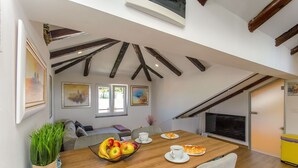 Ein Essbereich mit Holztisch, Stühlen, Obstschale und Fernseher an der Wand.