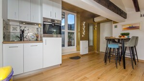 Eine moderne Küche mit weißen Schränken, einem eingebauten Backofen und einem Essbereich mit Tisch und Stühlen.