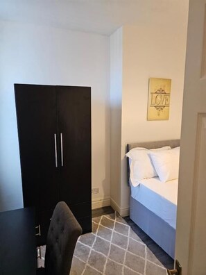 Un dormitorio con cama, armario, silla y pared con un cartel que dice 'LOVE'.