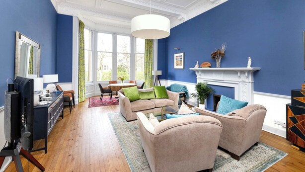 A living room with a blue wall, a fireplace, and a large window.