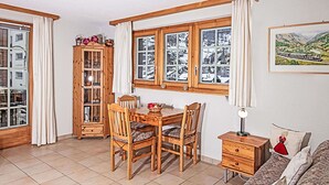 Una habitación acogedora con una mesa de madera, sillas, un armario y un sofá.