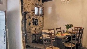 A rustic dining area with a stone wall, wooden ceiling beams, and a chandelier. - Wonderful private villa for 4 people with patio and pets allowed (Someo)