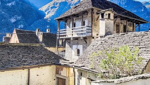 A traditional stone building with a balcony, set against a backdrop of snow-capped mountains. - Wonderful private villa for 4 people with patio and pets allowed (Someo)