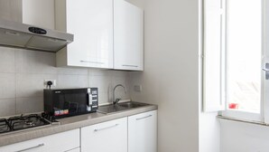 Une cuisine moderne avec des meubles blancs, une cuisinière à gaz, un four à micro-ondes et une fenêtre donnant sur l’extérieur.