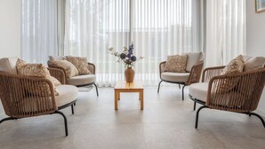 Una sala de estar con cuatro sillas de mimbre, una mesa de centro de madera y un jarrón con flores.
