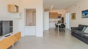 A modern living room with a TV, sofa, and dining area. - Beautiful apartment for 5 guests with WIFI, TV, patio and panoramic view (Riva Del Garda)