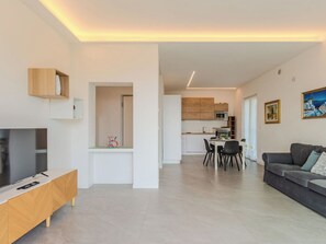 Ein modernes Wohnzimmer mit Fernseher, Sofa und Essbereich.