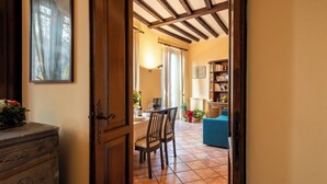 Une pièce avec une porte en bois, une table à manger avec des chaises, un canapé bleu et une bibliothèque.