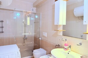 Une salle de bain avec une douche à parois de verre, des toilettes, un lavabo avec un miroir et un porte-serviettes.