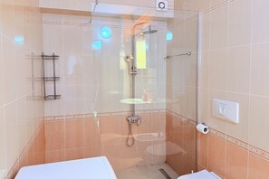 A glass-enclosed shower with a handheld showerhead, a towel rack, and a toilet paper holder. - Beachfront Apartment In Durres 072 (Durrës)