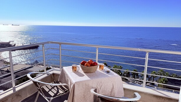 Un balcon avec une table dressée pour deux personnes, donnant sur la mer.