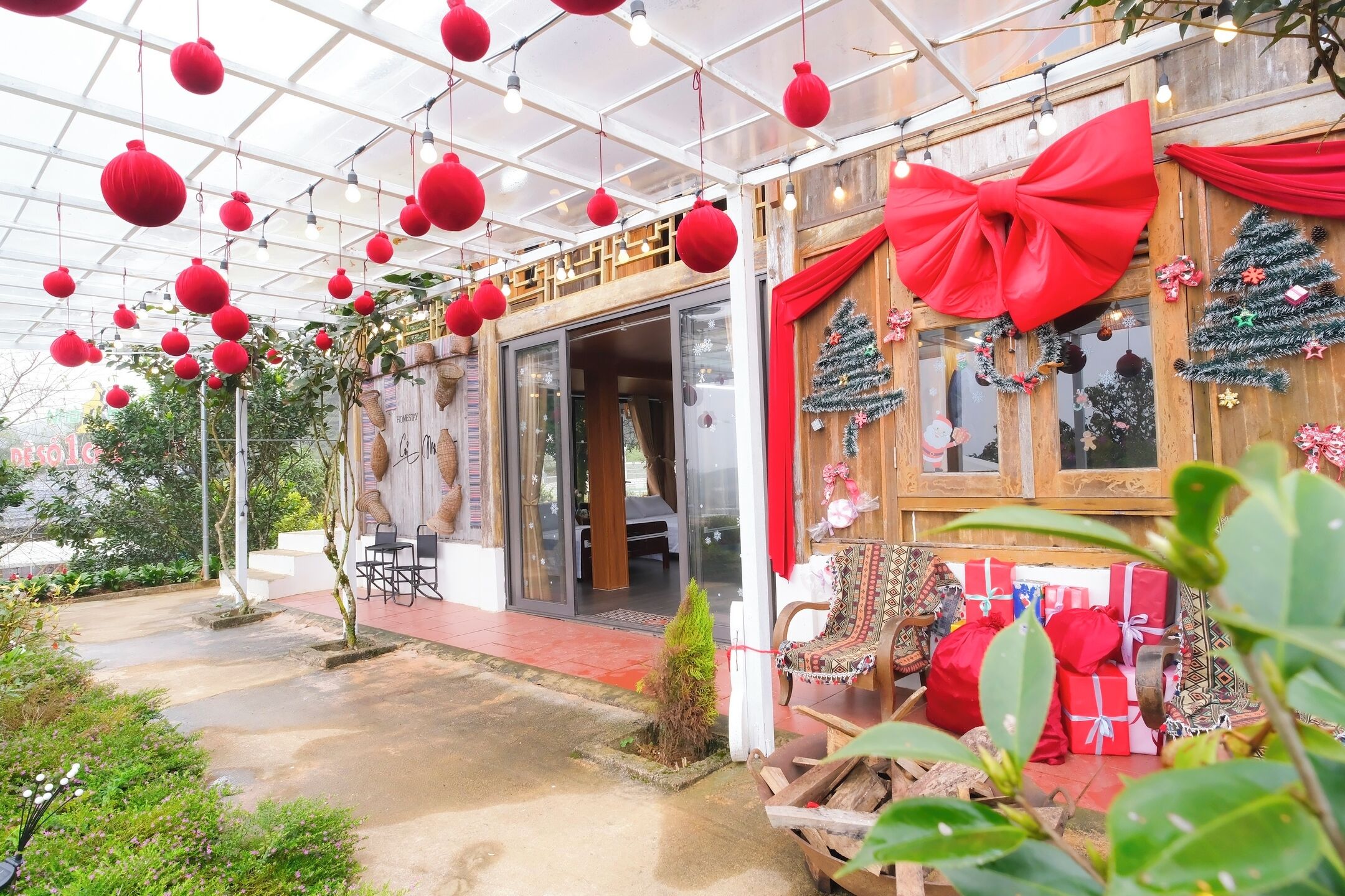 A greenhouse with red decorations, a wooden bench, and a Christmas tree.