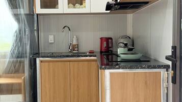 Uma cozinha compacta com armários de madeira, uma pia de aço inoxidável e um balcão pequeno.