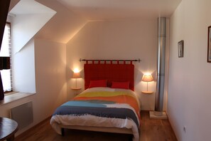 Une chambre à coucher comprenant un lit, deux lampes de chevet, un radiateur, une fenêtre et un radiateur fixé au mur.