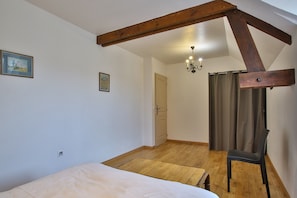 Une chambre avec un plafond en bois, un lit, une chaise, une porte et un lustre.
