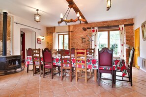 Un comedor con pared de ladrillo, sillas de madera, una mesa preparada para cuatro personas y una chimenea.