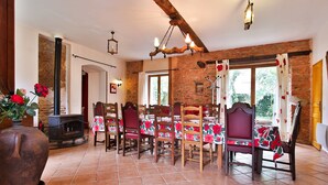 Zona pranzo con parete in pietra rustica, sedie di legno, pavimento piastrellato e tavolo apparecchiato.