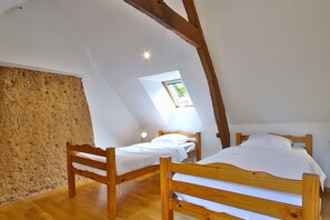 Una habitación con dos camas de madera, techo inclinado y tragaluz.