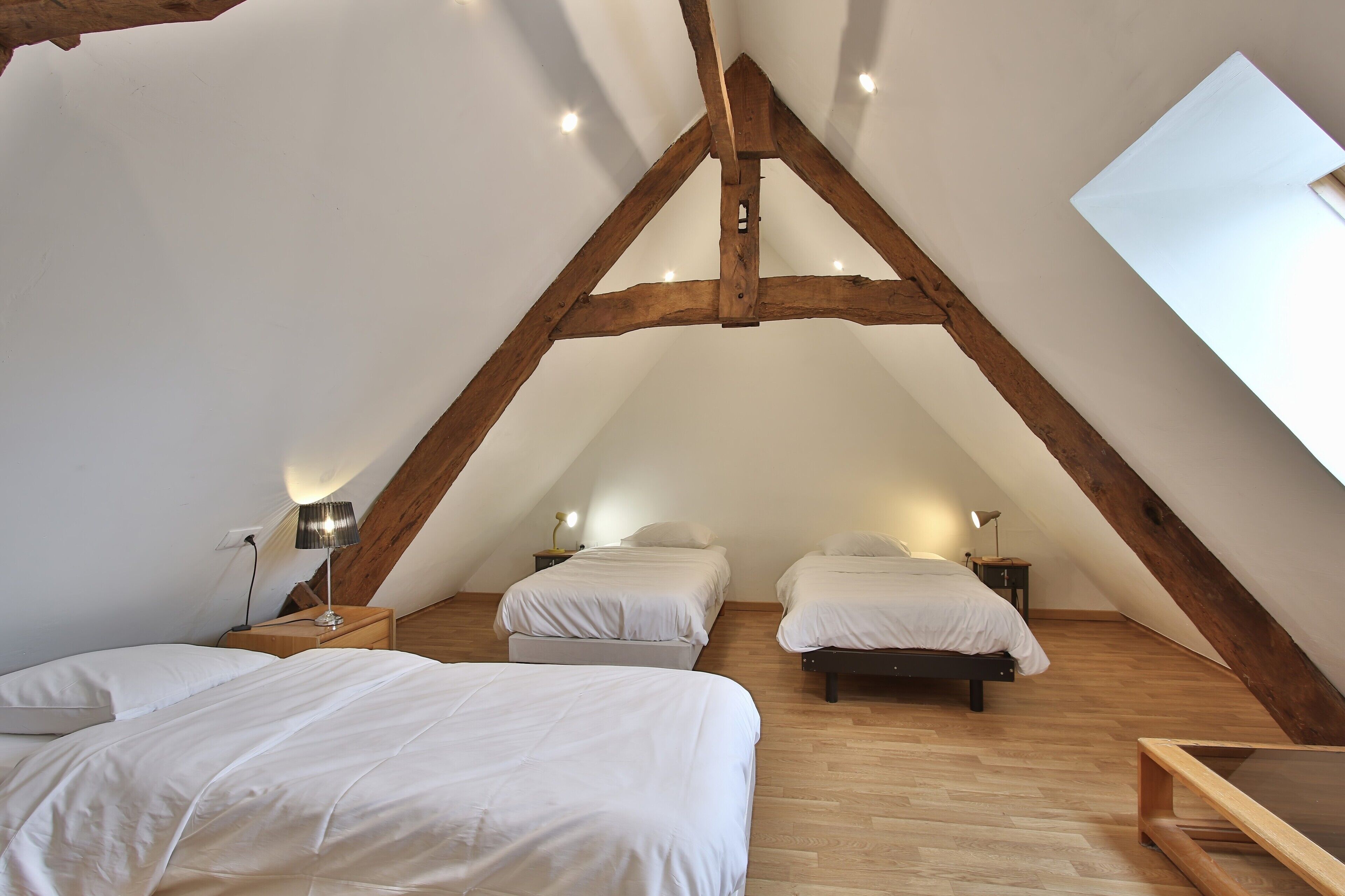 Een slaapkamer met twee bedden, houten balken en een schuine hemel.