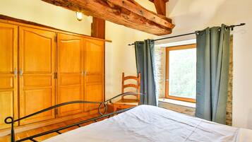 Un dormitorio con un armario de madera, estructura de cama de metal y ventana con cortinas.