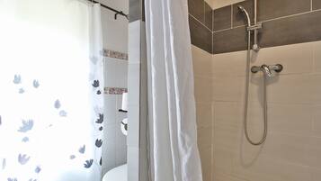 Un baño con ducha, inodoro y cortina estampada con motivos florales.