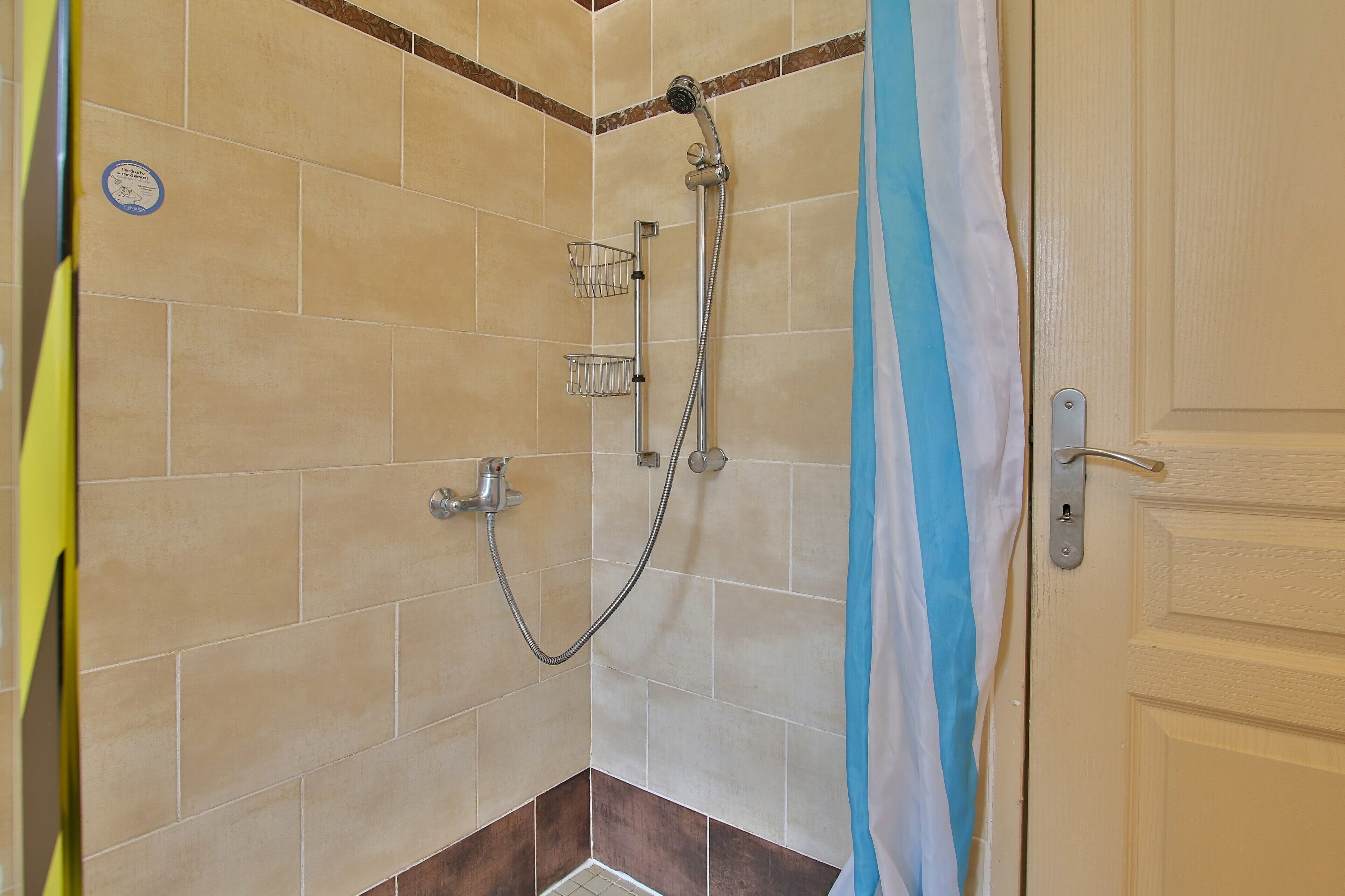 Een douche met een handdouche, een wandmengkraan en een douchemand.