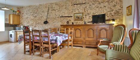 A dining area with a stone wall, wooden furniture, and a television.