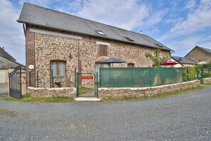 A stone building with a metal gate and a sign that reads 'CHARRETERIE.'
