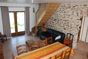 Et spiseområde med et bord, stole, en trappe, en stenvæg og en sort lædersofa.