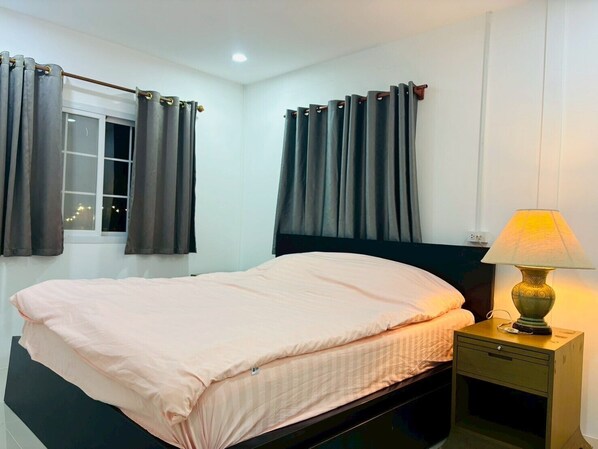 A bedroom with a bed, a nightstand, a lamp, and curtains. - Rose Park Resort (Phang Khon)