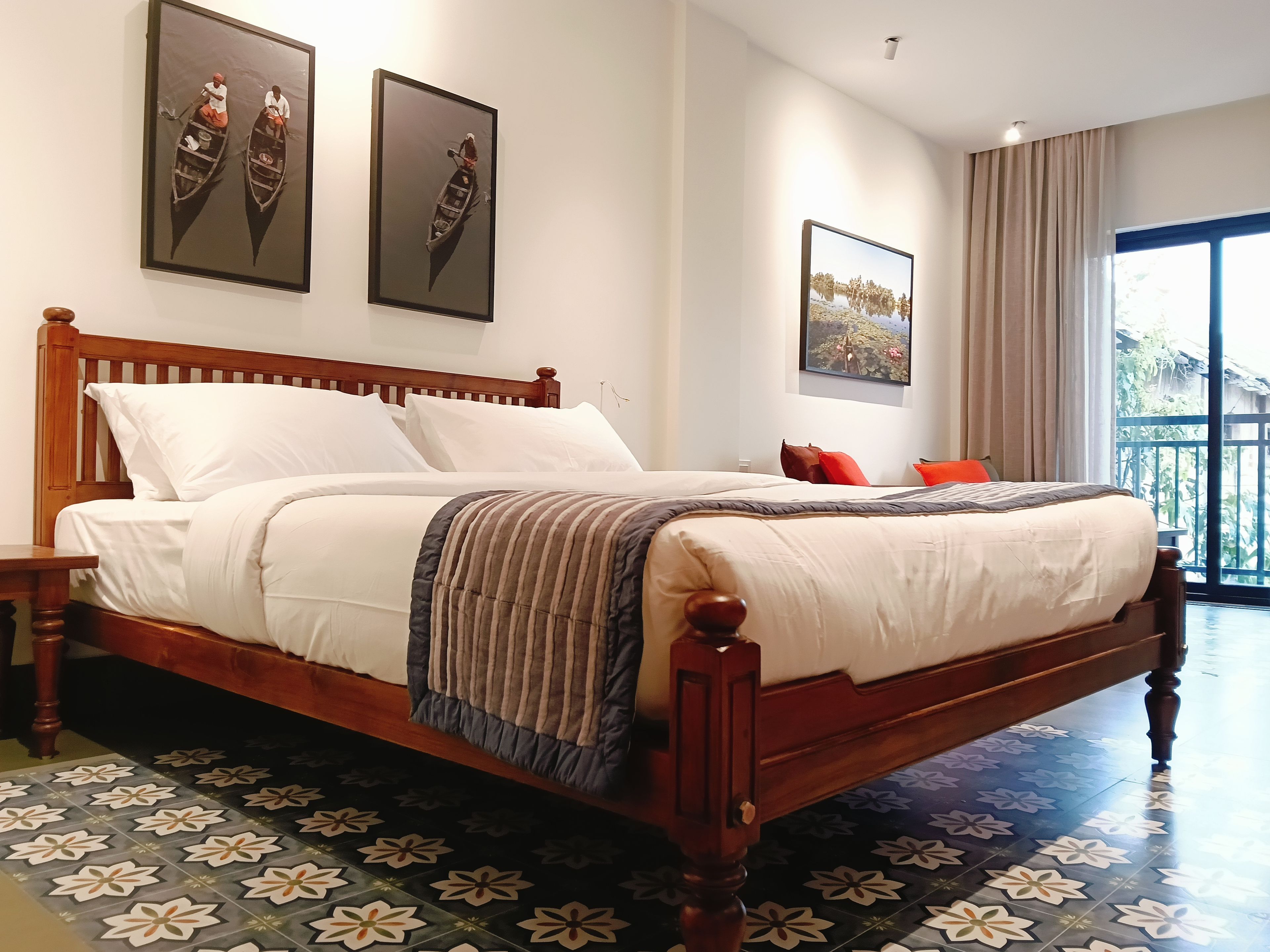 A hotel room with a wooden bed, a large window, and a balcony.