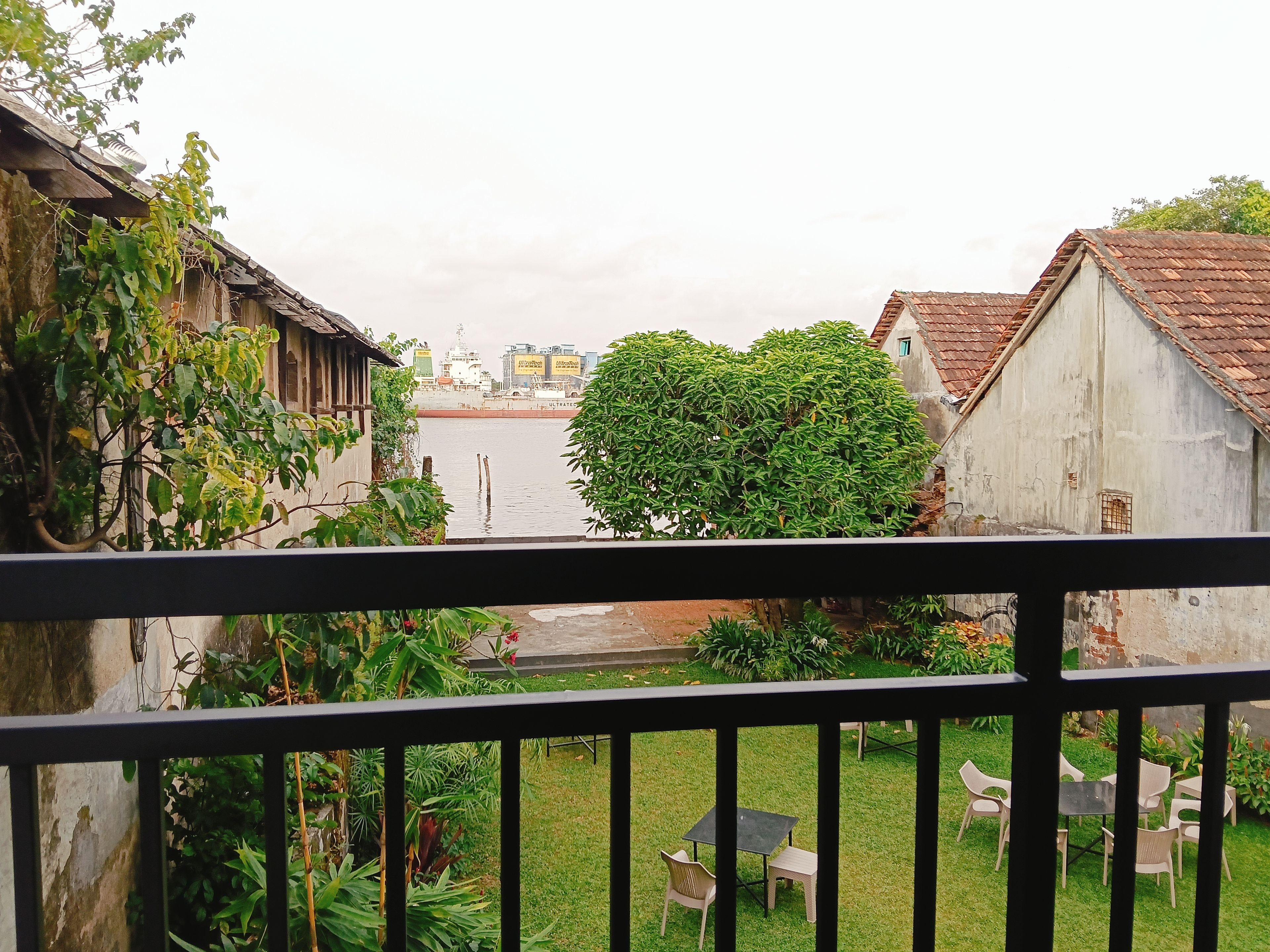 Uitzicht vanaf een balkon met een hekwerk, op een rivier, een grasveld met een tafel en stoelen en gebouwen met een rustieke uitstraling.