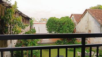 Uitzicht vanaf een balkon met een hekwerk, op een rivier, een grasveld met een tafel en stoelen en gebouwen met een rustieke uitstraling.