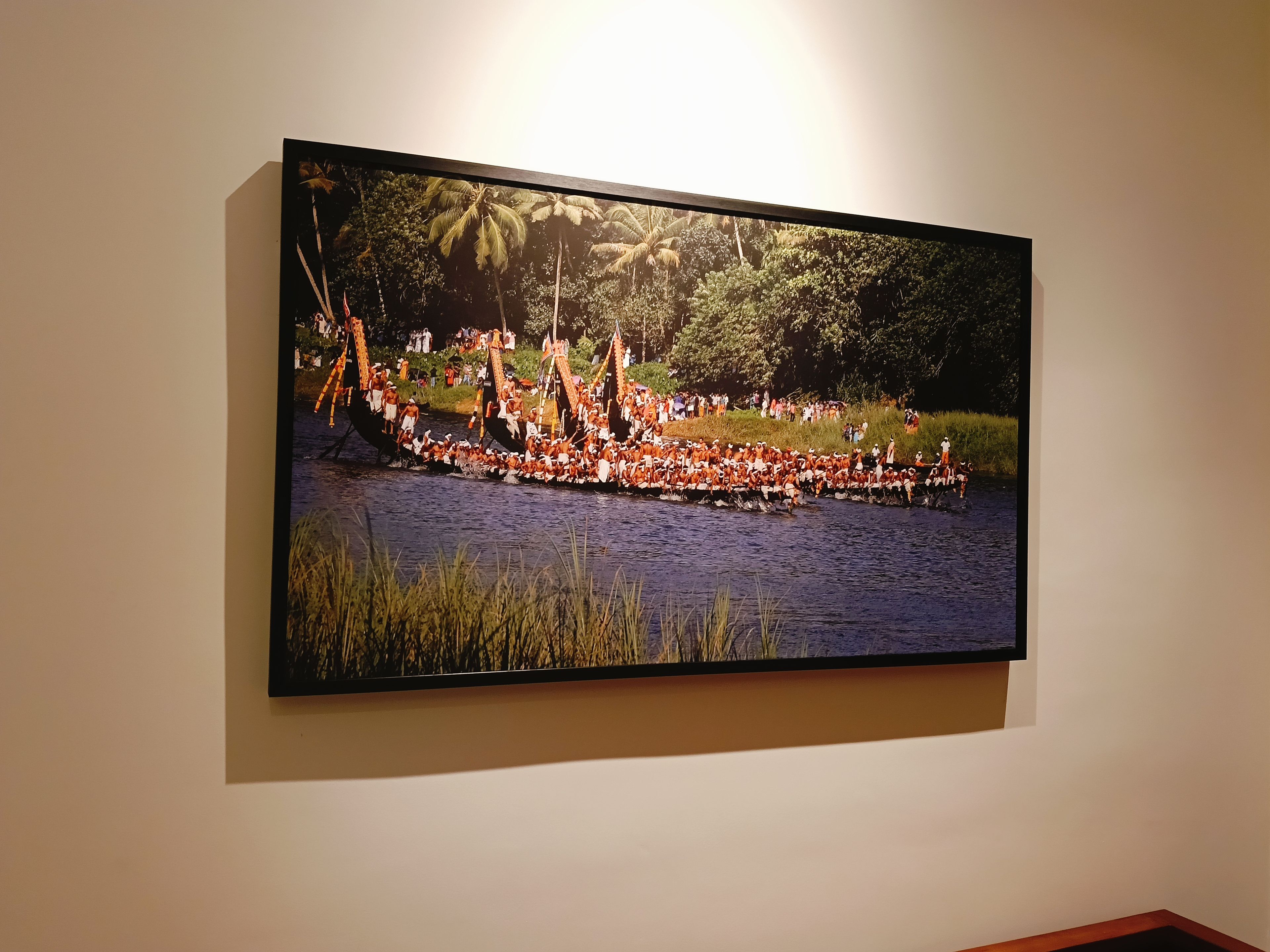 Un televisor de pantalla plana grande montado en una pared mostrando un barco tradicional con gente.