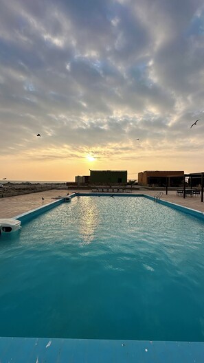 A swimming pool with a sunset in the background. - Roushan Resort  (Mirbat)