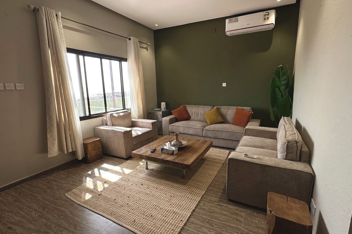 A living room with a sofa, coffee table, and a large window with curtains.