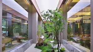 A modern indoor garden with a central tree, seating area, and glass walls reflecting the interior. - Langyun Garden Hotel (Guilin)