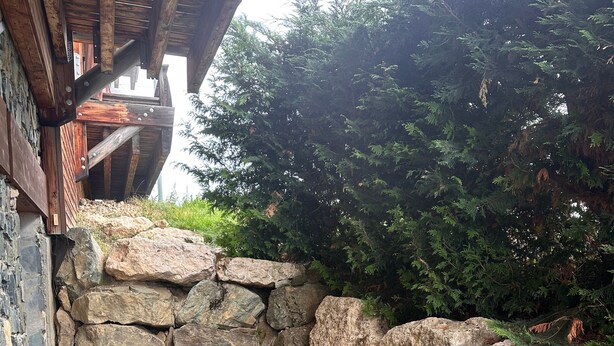 A wooden deck with a stone wall and a bench. - Apartment "La Cabane" in Chamrousse, Private Terrace, Ski-in/Ski-out (Chamrousse)