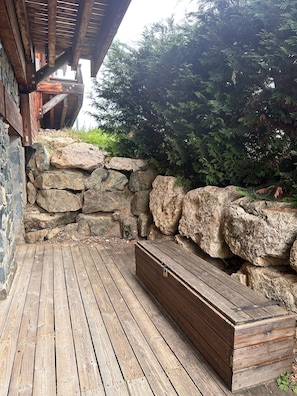 Una terraza de madera con un muro de piedra y un banco.