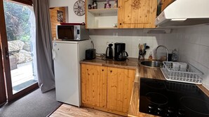 A compact kitchen with wooden cabinets, a microwave, a coffee maker, and a sink. - Apartment "La Cabane" in Chamrousse, Private Terrace, Ski-in/Ski-out (Chamrousse)