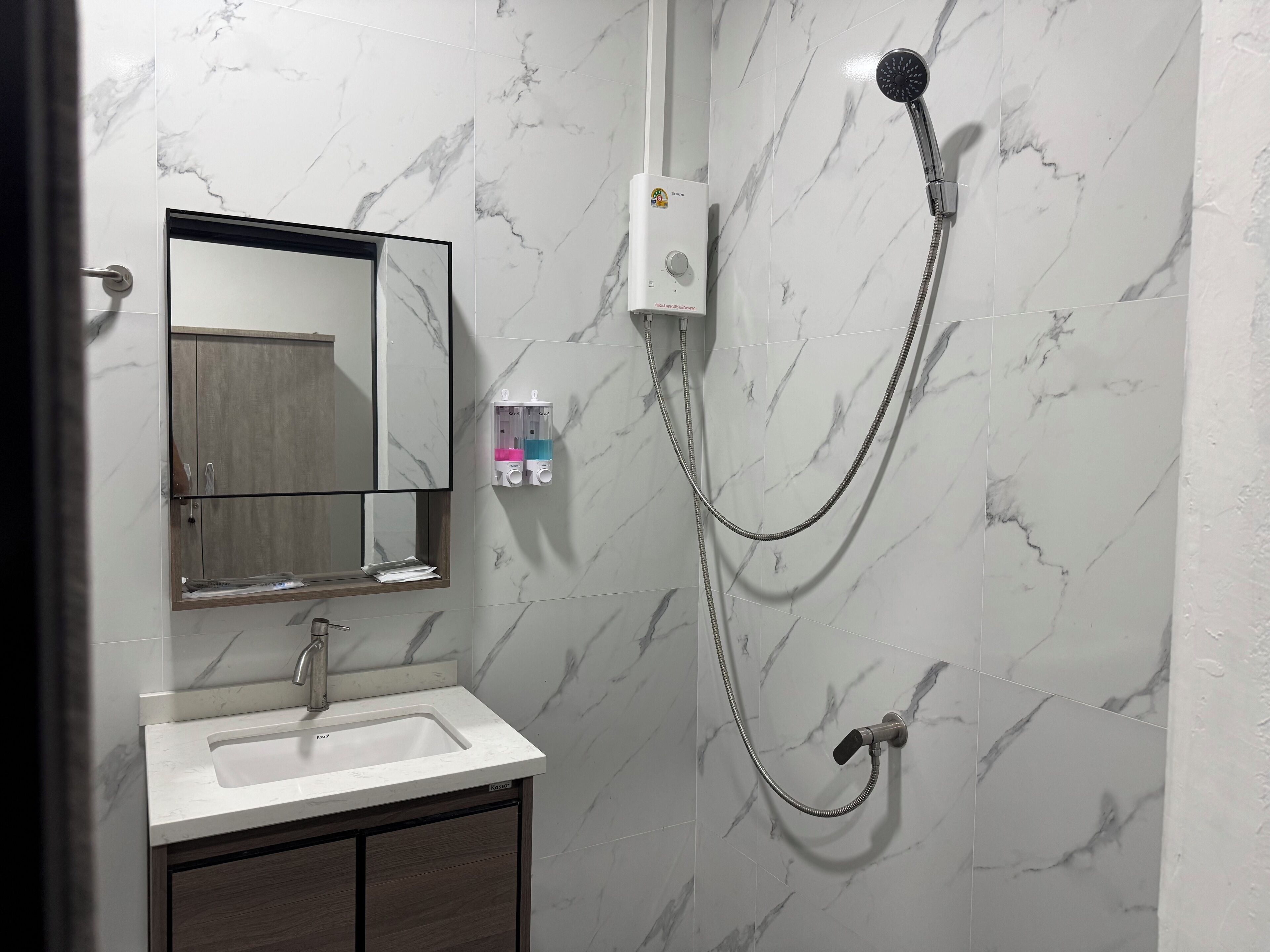 Een badkamer met een wastafel, spiegel en douche.