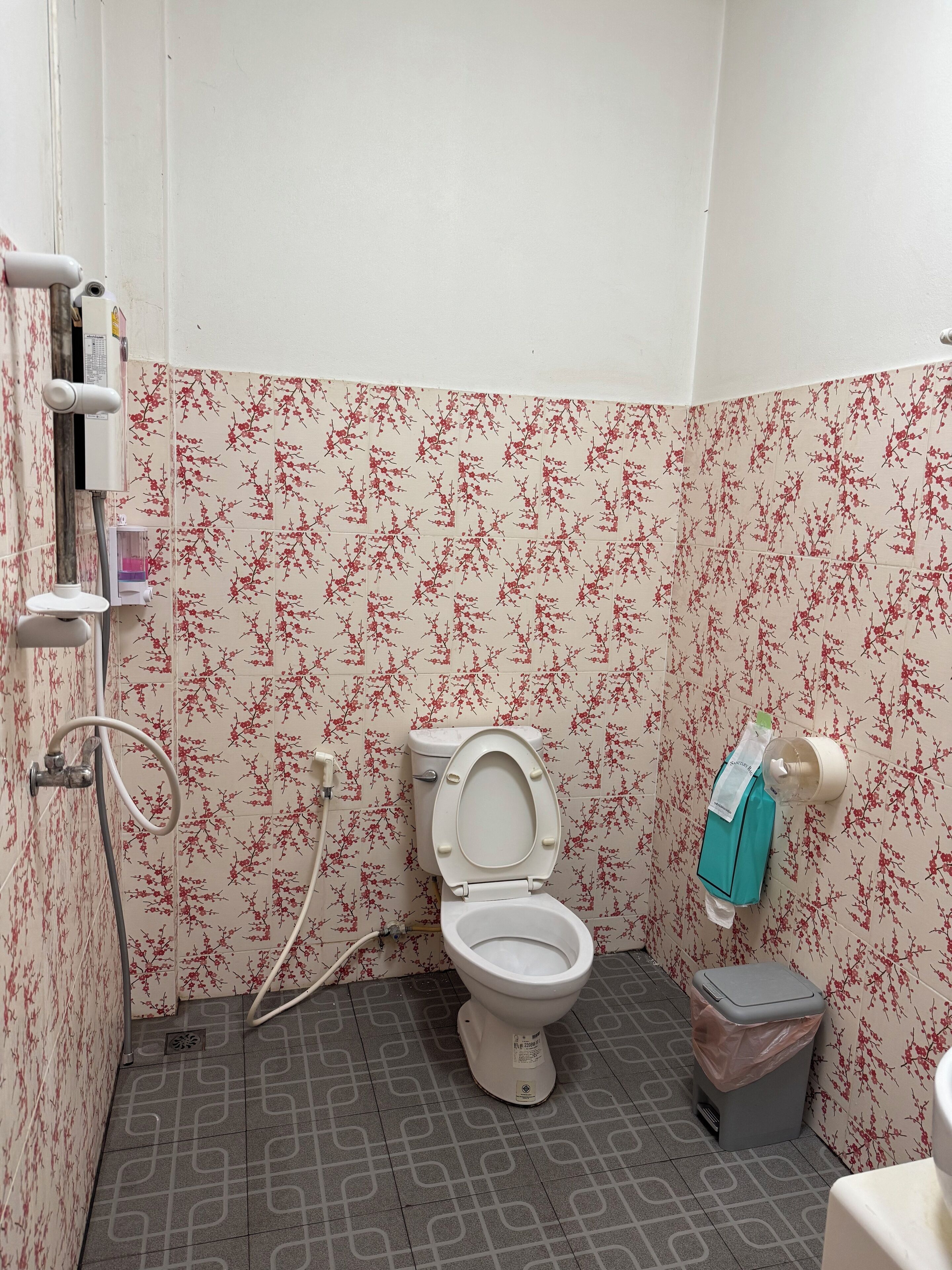 A small bathroom with a toilet, a shower, and a trash bin.