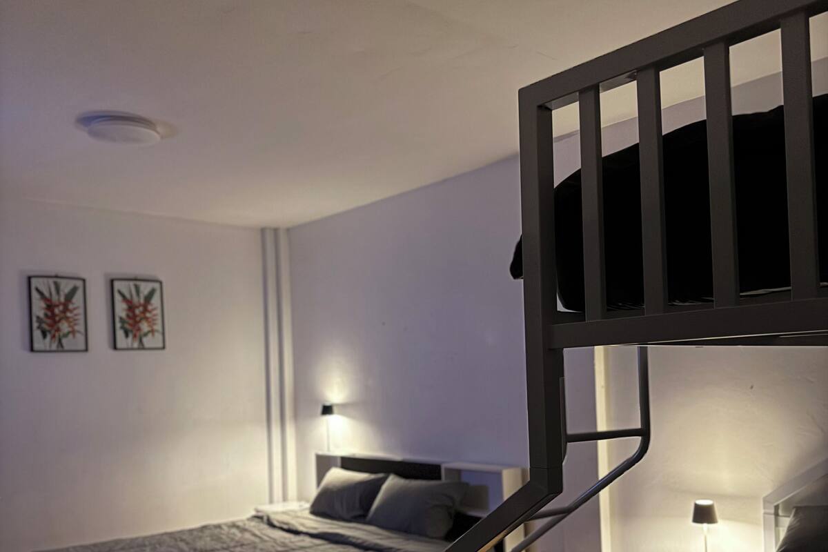 Ein Schlafzimmer mit Etagenbetten, einem Nachttisch, einer Lampe und zwei gerahmten Bildern an der Wand.