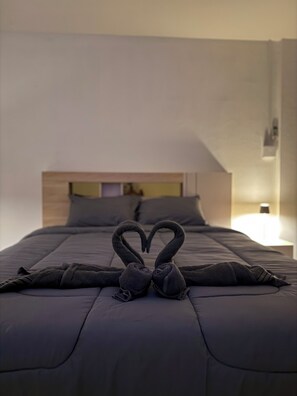 Un llit amb una tovallola disposada en forma de cor i una làmpada de nit.