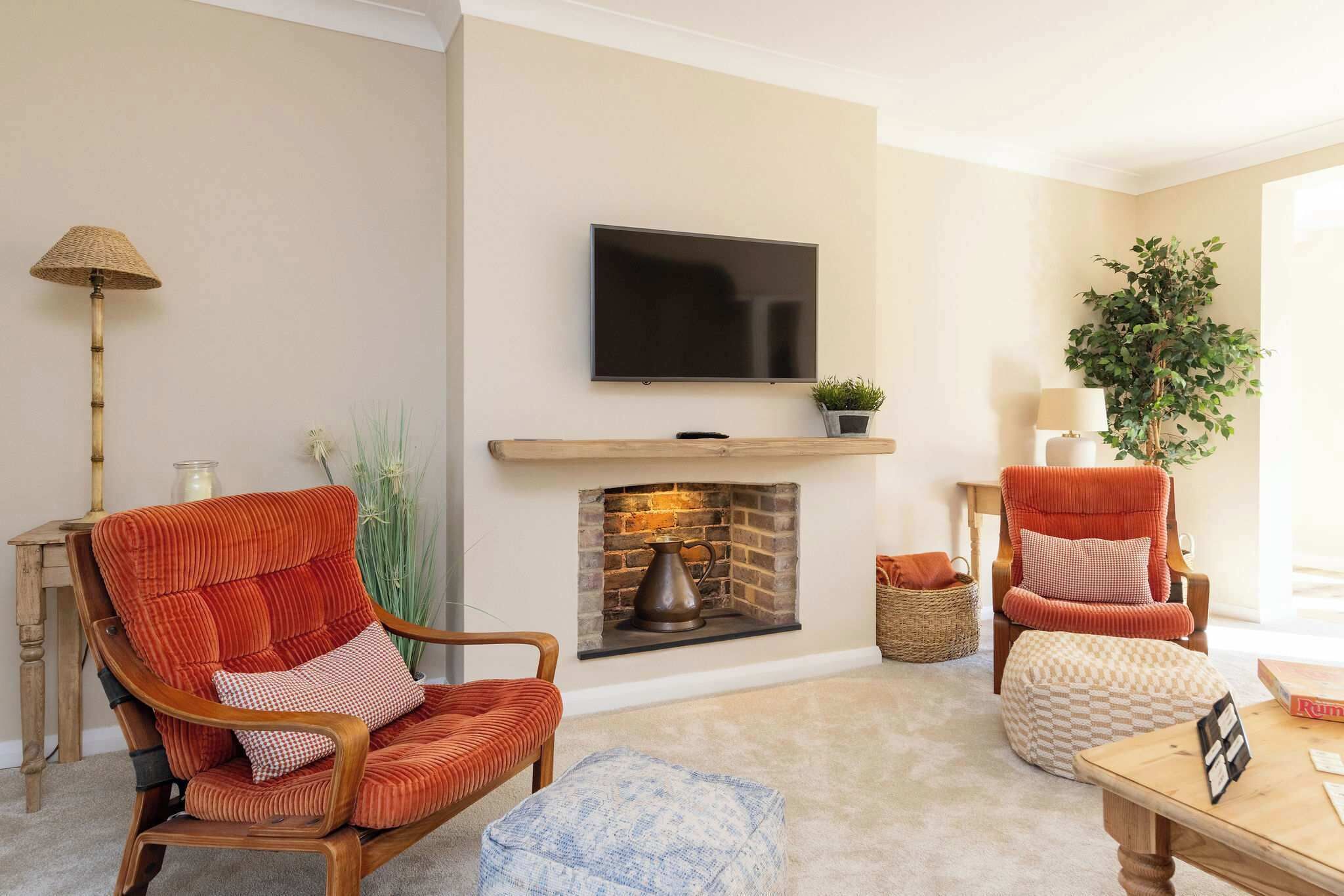 A living room with a fireplace, a television mounted above it, and two armchairs.