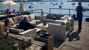 Ein Außenbereich mit Sofas und einem Tisch, mit Blick auf einen Yachthafen und Boote.